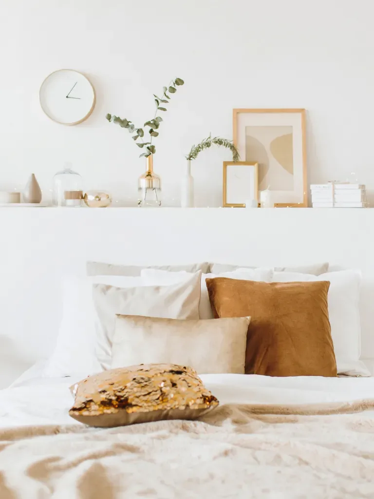 Chambre blanche, coussins ocre et étagère de décoration au-dessus du lit