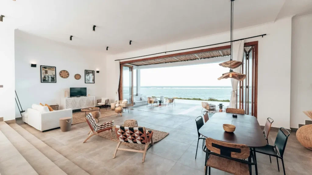 Séjour lumineux ouvert sur la mer, table en bois et plantes