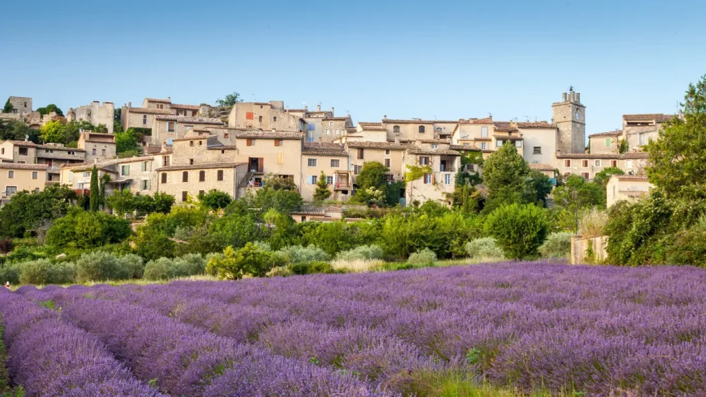 Village provençal aux maisons de pierre, devant un champ de lavande